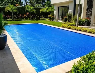 Alberca protegida con cubierta solar azul en jardín